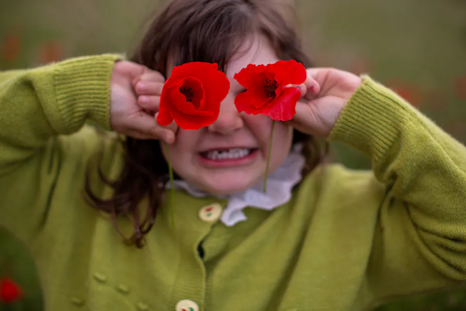 Kind spielt mit roten Blüten
