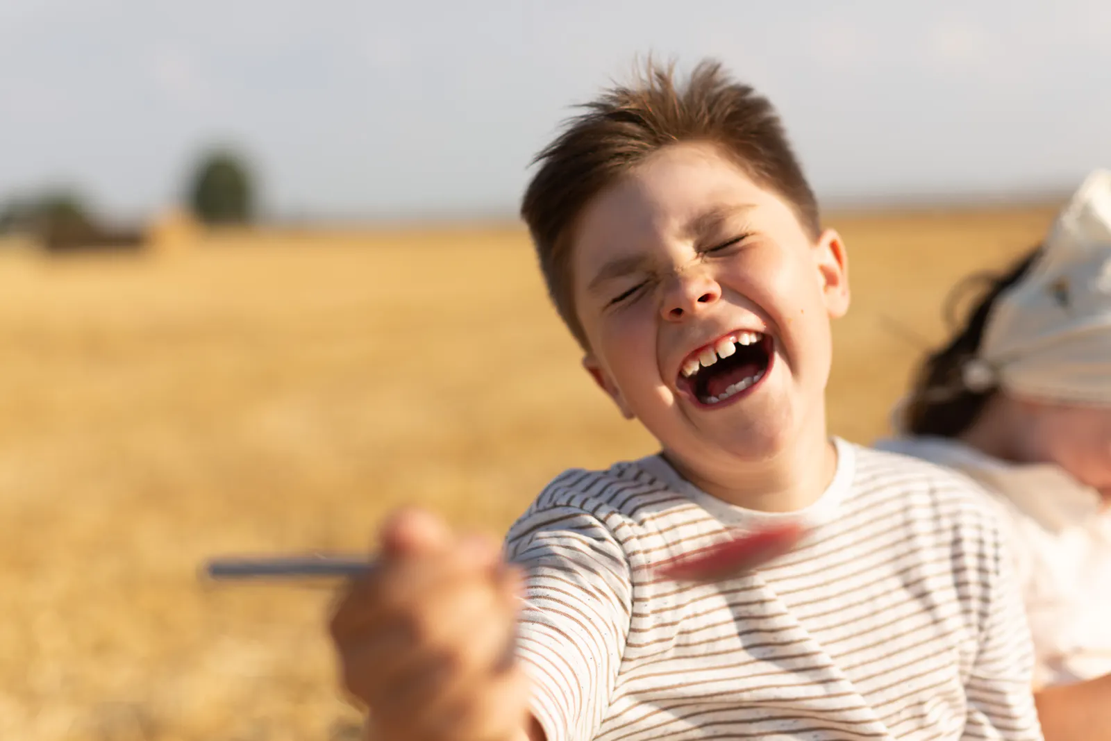 Lachender Junge bei einem Outdoor-Shooting